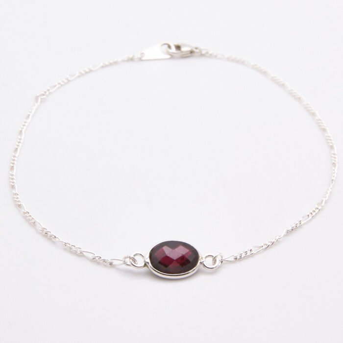 Sterling Silver Bezel-set Garnet Bracelet shown on flat white surface with focus on the Garnet