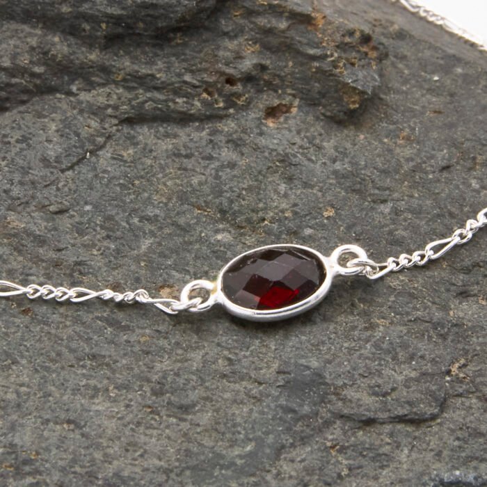 Sterling Silver Bezel-set Garnet Bracelet close up of Garnet on dark grey stone