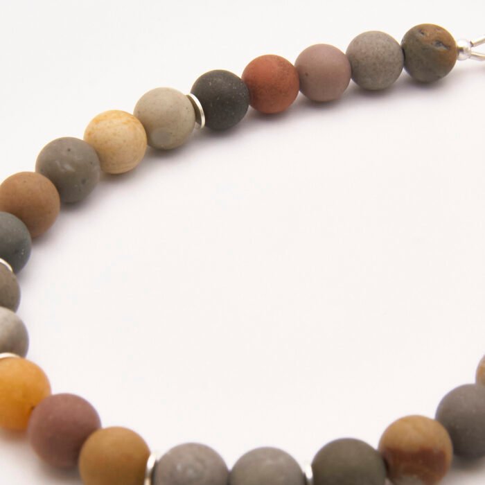 Natural Frosted Ocean Jasper and Sterling Silver Bracelet close up of beads on flat white surface
