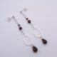 Garnet and Sterling Silver Deco Style Dangle Earrings Garnet and Sterling Silver Deco Style Dangle Earrings laid flat on white surface