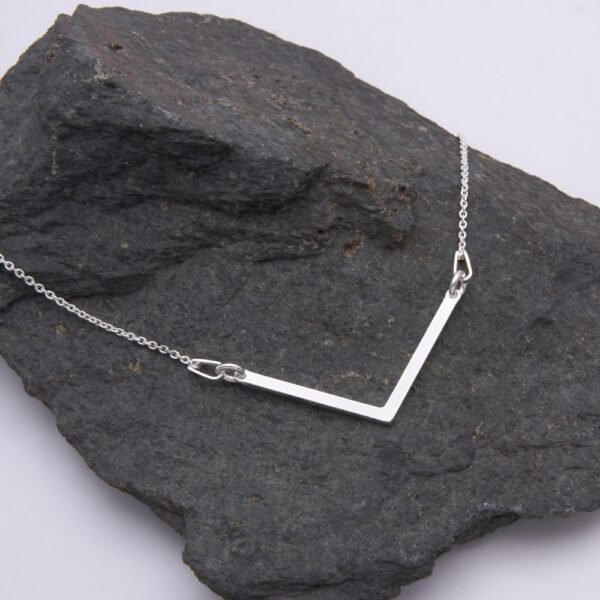 Sterling Silver Wide Angle Bar Necklace shown laid flat on dark grey stone