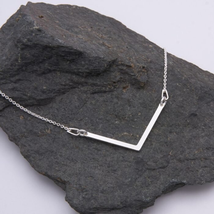 Sterling Silver Wide Angle Bar Necklace shown laid flat on dark grey stone