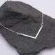 Sterling Silver Wide Angle Bar Necklace shown laid flat on dark grey stone