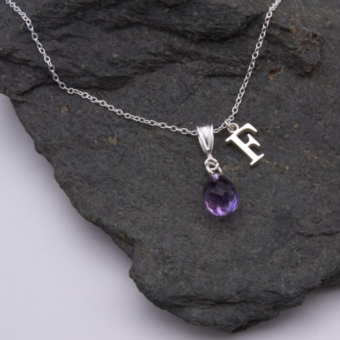 Amethyst Teardrop Pendant Necklace with added Initial Charm close up on dark grey stone