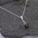 Garnet Ball and Sterling Silver Pendant Necklace close-up on stone