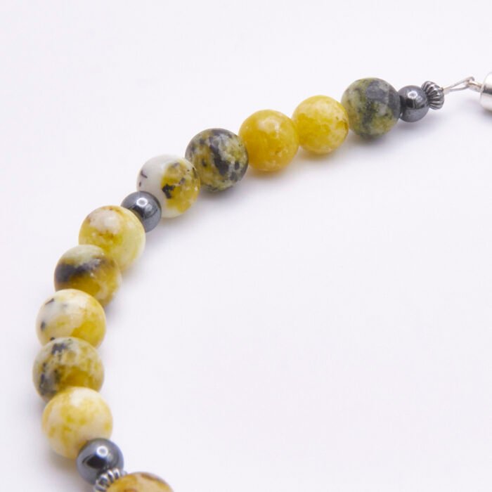 Yellow Turquoise and Hematite Sterling Silver Bracelet with Magnetic Clasp close up of part of bead strand on flat white surface