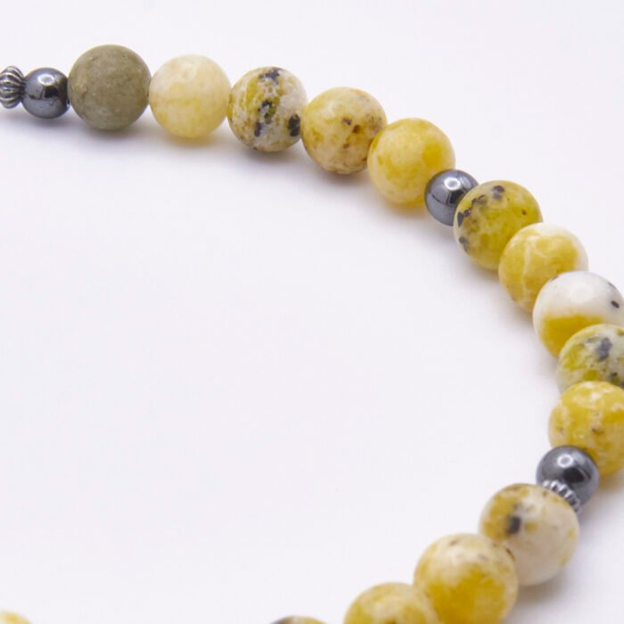 Yellow Turquoise and Hematite Sterling Silver Bracelet with Magnetic Clasp close up of part of bead strand on flat white surface