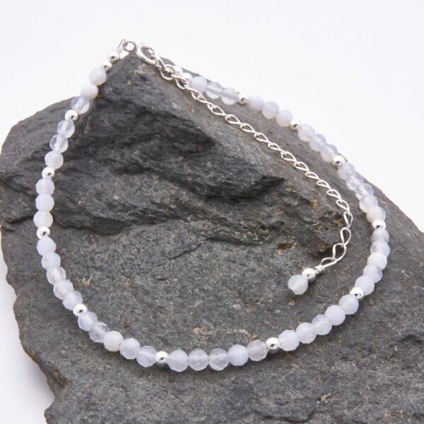 Blue Lace Agate and Sterling Silver Bracelet with extender chain with wire-wrapped bead decoration shown laid flat on a dark grey stone