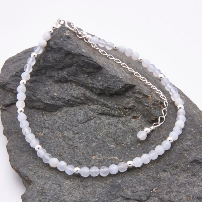 Blue Lace Agate and Sterling Silver Bracelet with extender chain with wire-wrapped bead decoration shown laid flat on a dark grey stone