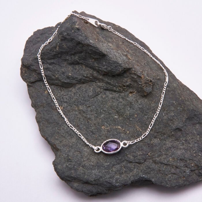 Sterling Silver Bezel-set Amethyst Bracelet with Figaro Chain shown on dark grey stone