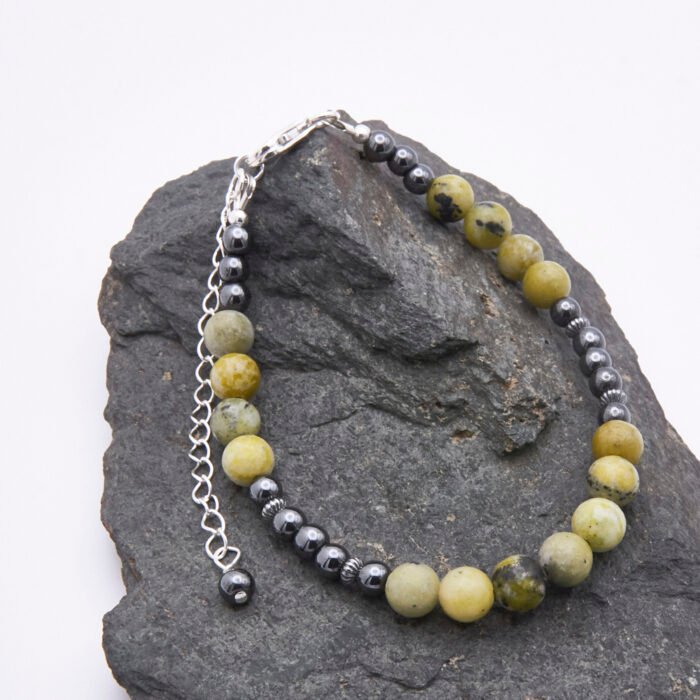 Yellow Turquoise and Hematite Bracelet with Lobster Clasp and Extender Chain shown on grey stone