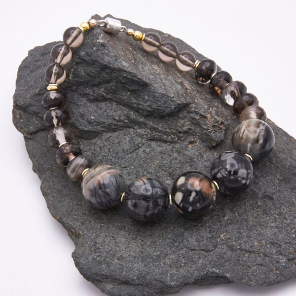 Picasso Jasper, Smoky Quartz and Smoky Watermelon Quartz Mixed Metals Bracelet with magnetic clasp shown laid flat on a dark grey stone