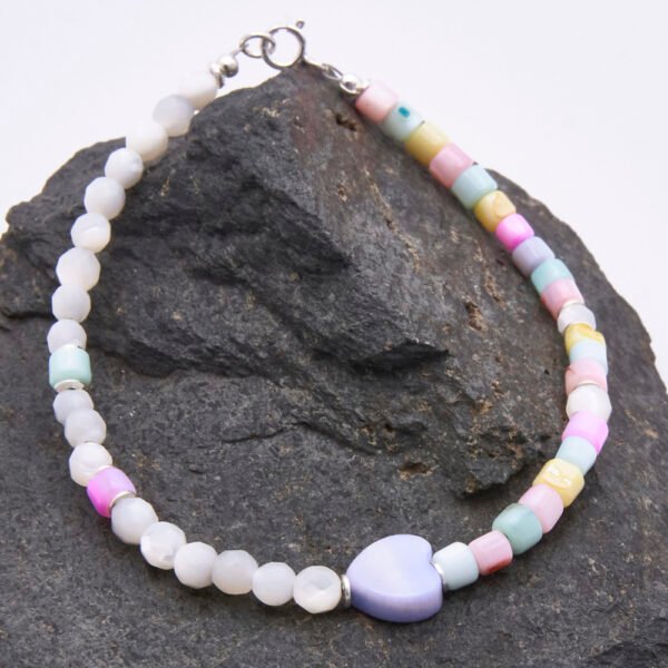 A colourful half and half bracelet comprising Mother of Pearl 4mm faceted rounds in a natural off-white colour and dyed Mother of Pearl cubes in pastel shades of yellow, pink, lilac, blue and green, all approximately 4mm diameter, together with a dyed pale lilac Mother of Pearl heart focal bead which is approximately 9mm at the widest point. The bracelet is finished with sterling silver spacers and a sterling silver spring ring clasp stamped 925