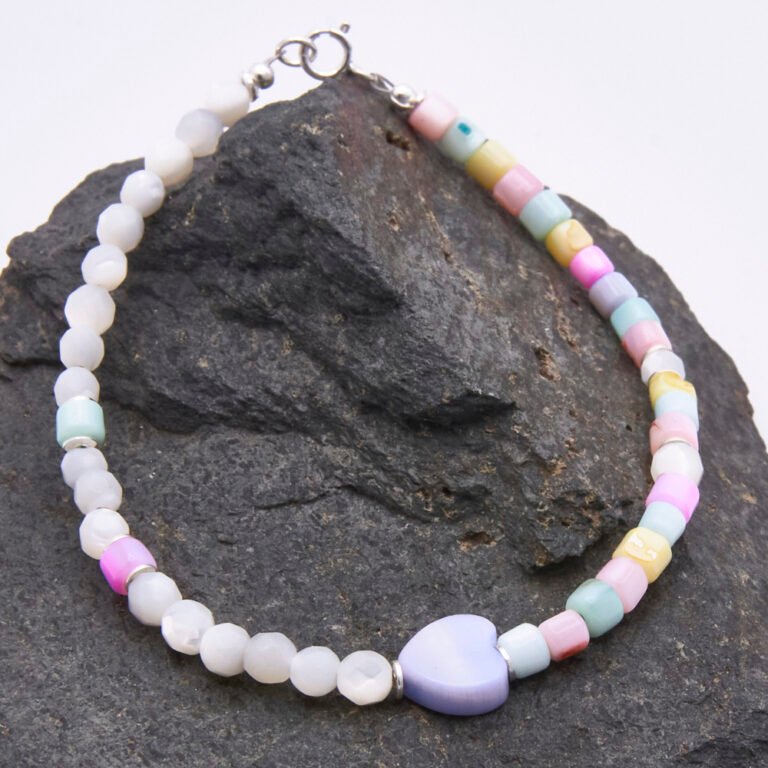 A colourful half and half bracelet comprising Mother of Pearl 4mm faceted rounds in a natural off-white colour and dyed Mother of Pearl cubes in pastel shades of yellow, pink, lilac, blue and green, all approximately 4mm diameter, together with a dyed pale lilac Mother of Pearl heart focal bead which is approximately 9mm at the widest point. The bracelet is finished with sterling silver spacers and a sterling silver spring ring clasp stamped 925