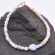 A colourful half and half bracelet comprising Mother of Pearl 4mm faceted rounds in a natural off-white colour and dyed Mother of Pearl cubes in pastel shades of yellow, pink, lilac, blue and green, all approximately 4mm diameter, together with a dyed pale lilac Mother of Pearl heart focal bead which is approximately 9mm at the widest point. The bracelet is finished with sterling silver spacers and a sterling silver spring ring clasp stamped 925