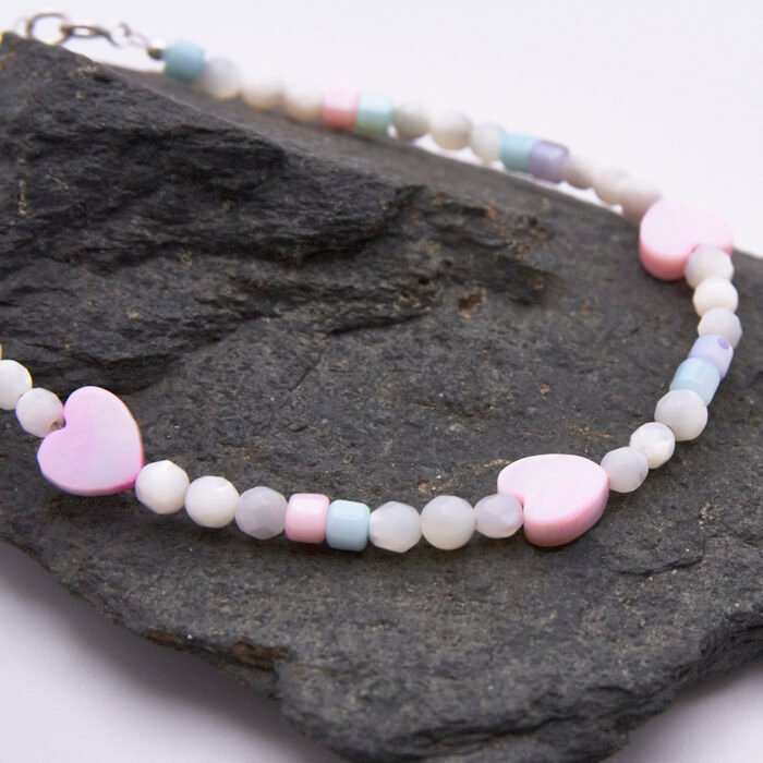 Mother of Pearl Heart Trio Bracelet close up of beads and hearts shown on dark grey stone