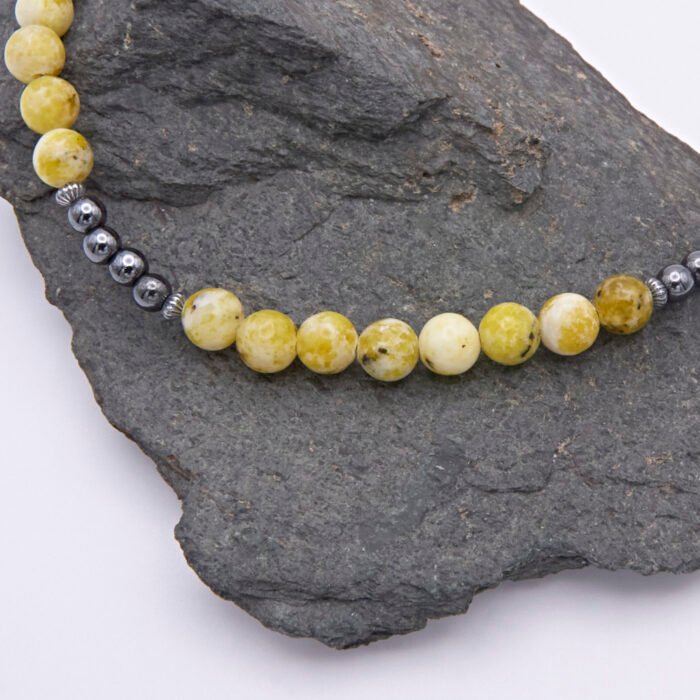 Yellow Turquoise and Hematite Necklace close up of beaded sections on grey rock