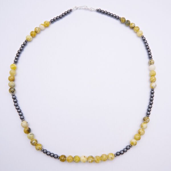 Yellow Turquoise and Hematite Sterling Silver Necklace with smooth round 6mm Yellow Turquoise beads and smooth round 3mm Hematite beads, punctuated with oxidised sterling silver corrugated saucer beads and finished with a Sterling Silver hook and eye clasp, top down view lying flat on plain white surface