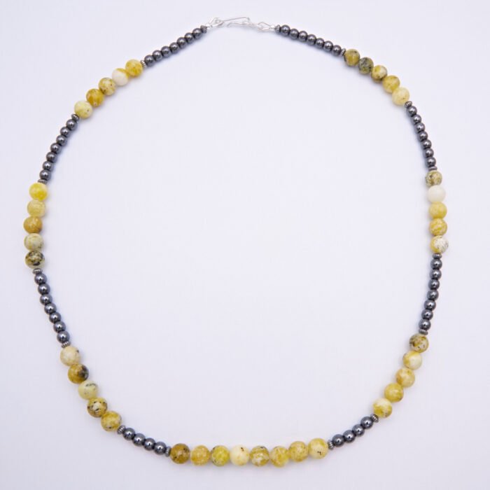 Yellow Turquoise and Hematite Sterling Silver Necklace with smooth round 6mm Yellow Turquoise beads and smooth round 3mm Hematite beads, punctuated with oxidised sterling silver corrugated saucer beads and finished with a Sterling Silver hook and eye clasp, top down view lying flat on plain white surface