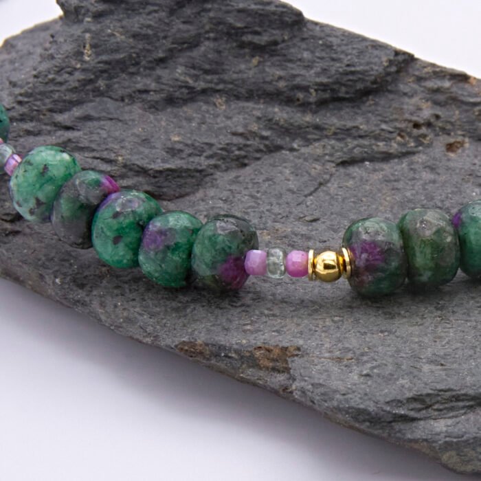 Ruby, Green Apatite and Ruby Zoisite Necklace close up of Ruby and Green Apatite beads between Ruby Zoisite sections on grey stone