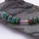Ruby, Green Apatite and Ruby Zoisite Necklace close up of Ruby and Green Apatite beads between Ruby Zoisite sections on grey stone
