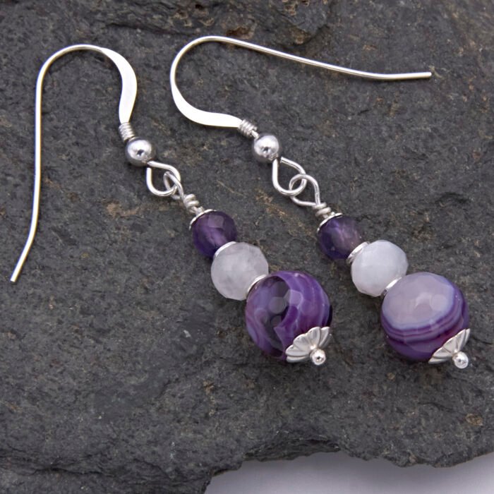 Purple Banded Agate, Rainbow Moonstone and Amethyst Sterling Silver Drop Earrings Purple Banded Agate, Rainbow Moonstone and Amethyst Sterling Silver Drop Earrings shown from above on dark grey stone