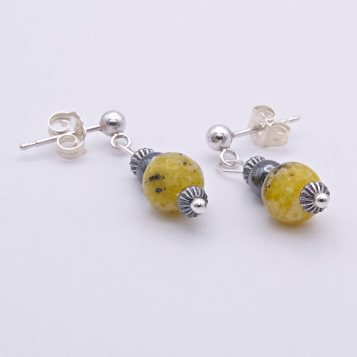 Yellow Turquoise and Hematite Sterling Silver dangles suspended from sterling silver stud ear posts with scroll backs, lying flat on white surface with focus on Yellow Turquoise