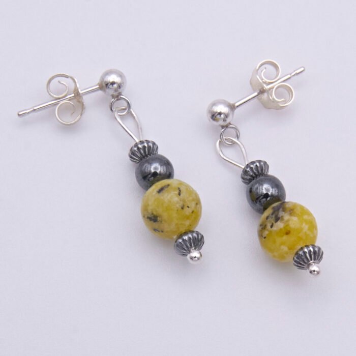 Yellow Turquoise and Hematite Sterling Silver dangles suspended from sterling silver stud ear posts with scroll backs, lying flat on white surface