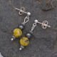 Yellow Turquoise and Hematite Sterling Silver dangles suspended from sterling silver stud ear posts with scroll backs, shown lying flat on grey stone