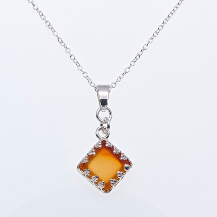 Carnelian Square Cabochon Sterling Silver Pendant Necklace close up of Carnelian pendant and bail on chain laid flat on white surface