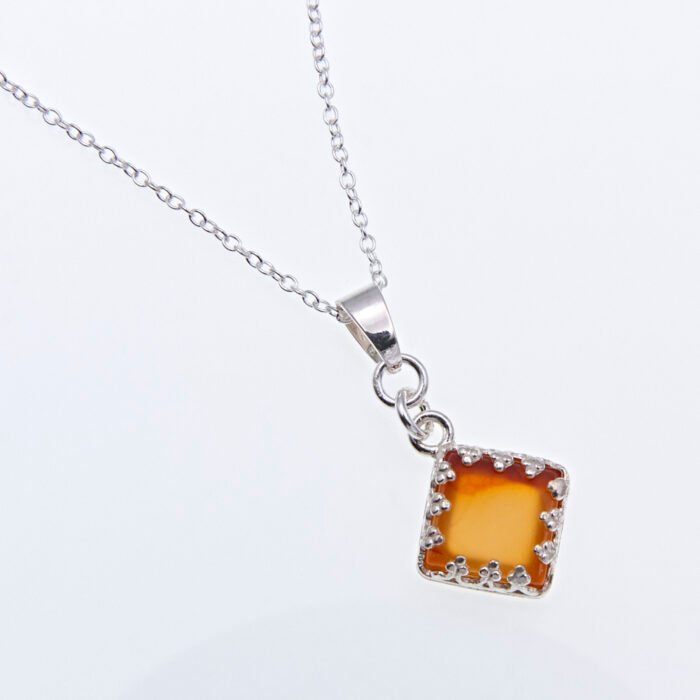 Carnelian Square Cabochon Sterling Silver Pendant Necklace angled close up of pendant and bail laid flat on a white surface