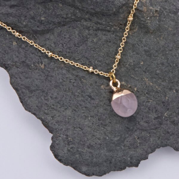 Rose Quartz Cabochon 24k Gold Plated Silver pendant on Gold Plated Satellite Chain close up view from above on dark grey stone