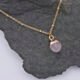 Rose Quartz Cabochon 24k gold plated silver pendant on gold plated satellite chain Rose Quartz Cabochon 24k Gold Plated Silver pendant on Gold Plated Satellite Chain close up view from above on dark grey stone