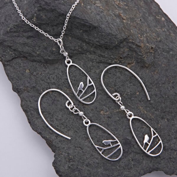 Sterling Silver Robin on Branch Pendant Necklace and Earrings set shown laid flat on dark grey stone