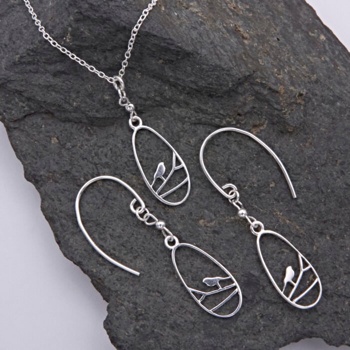 Sterling Silver Robin on Branch Pendant Necklace and Earrings set Sterling Silver Robin on Branch Pendant Necklace and Earrings set shown laid flat on dark grey stone