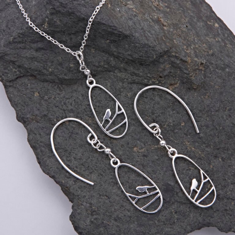 Sterling Silver Robin on Branch Pendant Necklace and Earrings set Sterling Silver Robin on Branch Pendant Necklace and Earrings set shown laid flat on dark grey stone