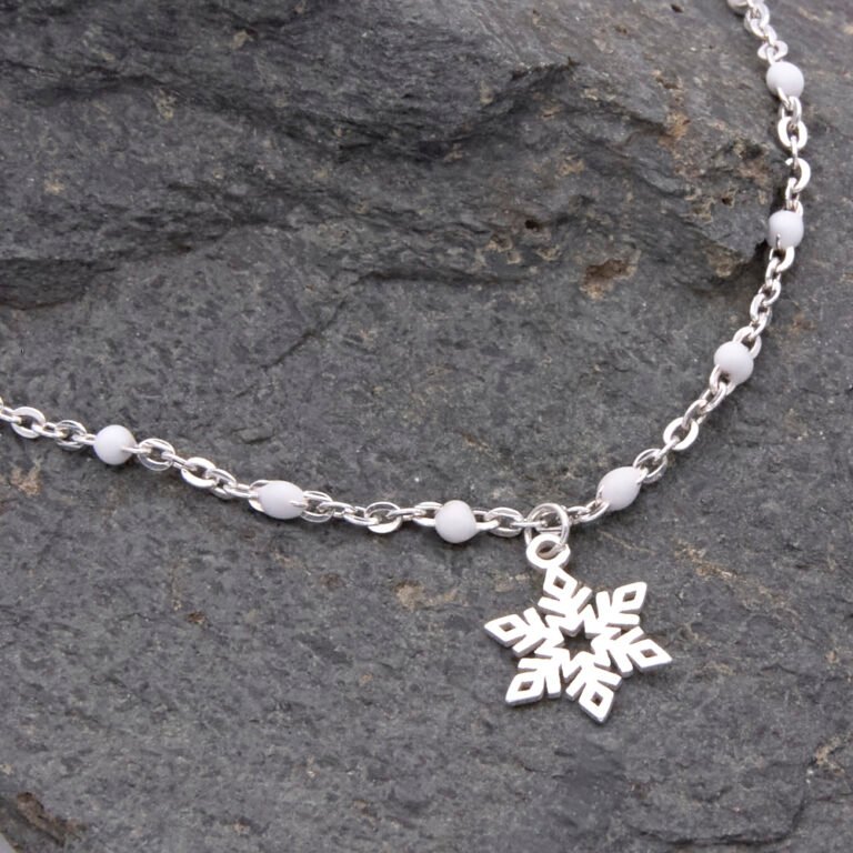 Sterling Silver and White Enamel Bead Bracelet with Sterling Silver Snowflake Charm shown laid flat on dark grey stone with close up of snowflake and part of chain