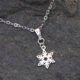 Sterling Silver Snowflake Charm Necklace, image shows close up of snowflake charm and bail on small area of chain, laid flat on dark grey stone