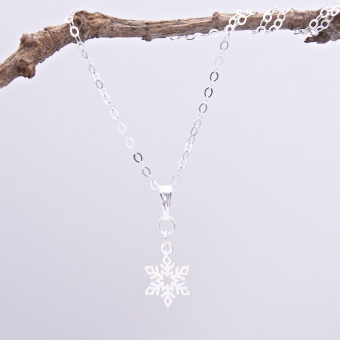 Sterling Silver Snowflake Charm Necklace, image shows necklace suspended from twig with plain white background