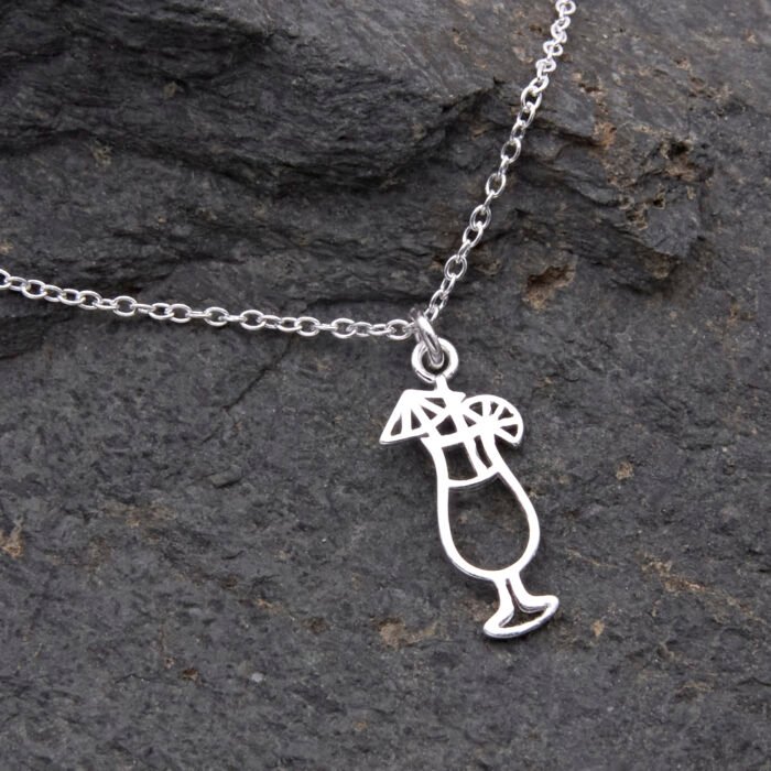 Sterling Silver Cocktail Charm Pendant Necklace, close up of cocktail charm and part of chain on dark grey stone, cocktail charm is at a slight angle
