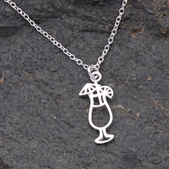 Sterling Silver Cocktail Charm suspended from a Sterling Silver chain, image shows close-up of cocktail and small portion of chain, laid flat on dark grey stone