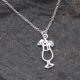 Sterling Silver Cocktail Charm suspended from a Sterling Silver chain, image shows close-up of cocktail and small portion of chain, laid flat on dark grey stone