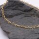 Gold Heart Link Chain Bracelet, close-up image of part of the chain, on dark grey stone