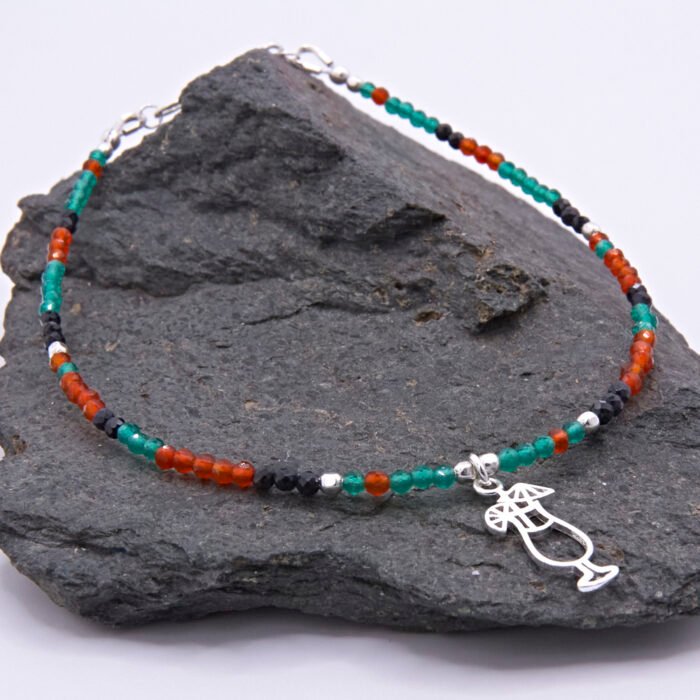 Green Onyx, Carnelian and Sapphire Sterling Silver Bracelet with Sterling Silver Cocktail Charm in the centre, image shows bracelet draped at an angle over dark grey stone, with charm slightly to the right