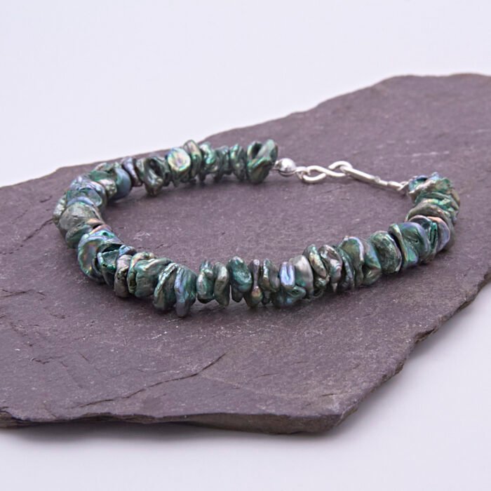 Green Keishi Cornflake Freshwater Pearl and Sterling Silver Bracelet, shown viewed from the side on dark slate