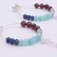 Mixed Gemstone Sterling Silver Hoop Earrings with Cocktail Charms shown laid flat on plain white surface, viewed close up from the side