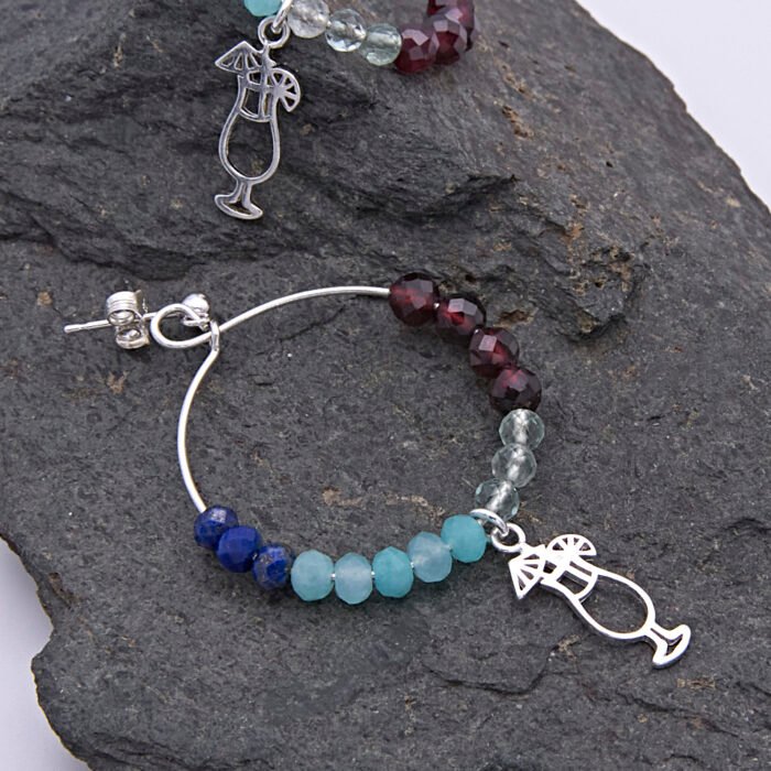 Mixed Gemstone Sterling Silver Hoop Earrings with Cocktail Charms, image shows one complete earring and part of the other earring laid on dark grey stone