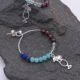 Mixed Gemstone Sterling Silver Hoop Earrings with Cocktail Charms, image shows one complete earring and part of the other earring laid on dark grey stone