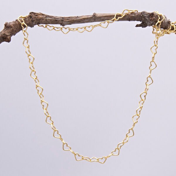 Gold Heart Link Chain Necklace shown hanging from a twig