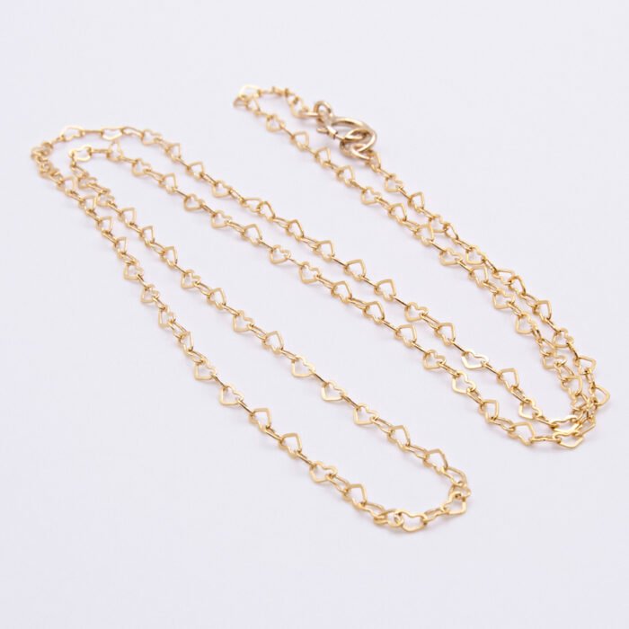 Gold Filled Tiny Hearts Chain Necklace laid on plain white background, looped into an N shape, at a slight angle